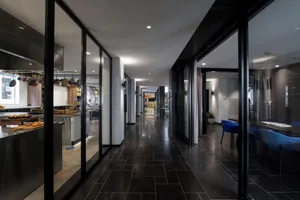 A modern restaurant corridor featuring glass walls.