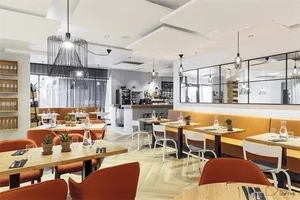 A modern restaurant interior with wood tables, chairs, and flooring.