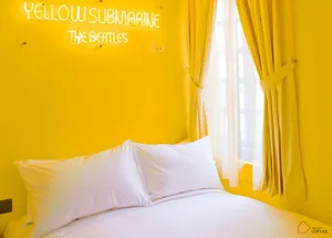A minimalist bedroom with yellow walls, a white bed, and yellow curtains.
