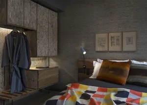Industrial-style bedroom with wood furnishings, concrete walls, and colorful textiles.