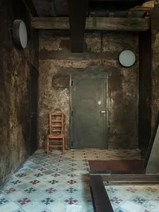 Industrial-style interior with a green metal door and wooden chair on a patterned tiled floor.