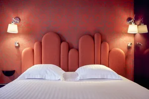 Modern bedroom with an orange upholstered headboard and white bedding.