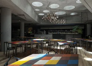 A minimalist restaurant interior featuring concrete walls, wooden floors, and glass elements.