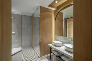 Modern bathroom with metallic accents and marble finishes, featuring a walk-in shower and double sink vanity.