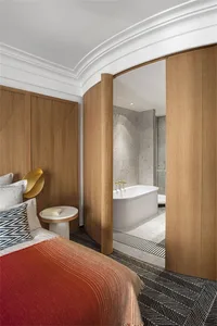 Modern bedroom suite featuring wooden furnishings and a marble bathroom with a freestanding bathtub.