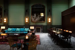A modern restaurant lounge with marble walls, concrete flooring, and rattan furniture.