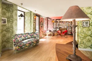 Modern living room with a floral-patterned sofa, wooden flooring, and bookshelves.