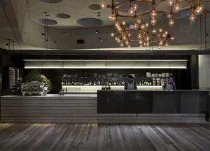 A modern restaurant bar featuring concrete, wood, glass, and metal materials