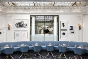 Modern restaurant interior with blue circular seating, white walls, and black-and-white artwork.