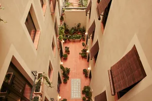 Modern, industrial-style courtyard facade with a terrazzo floor, greenery, and natural light.