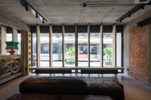 Modern office space featuring polished concrete floors, glass walls, and sleek leather furniture.