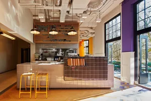 A modern cafe interior with a concrete kitchen bar and tile backsplash.
