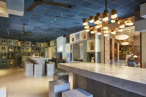 Industrial-style bar with concrete counter top, metal stools, and wooden cabinets.