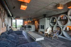 An industrial living room featuring brick walls, concrete flooring, and wooden furniture.