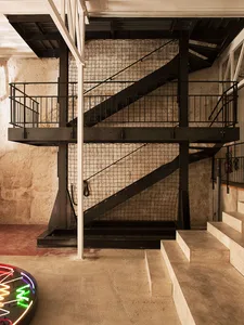 Industrial-style staircase with a metal grid railing and black metal steps.