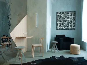A modern industrial living room featuring a concrete wall, wooden furniture, and minimalistic decor.