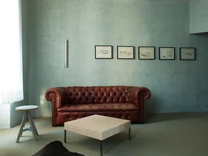 A modern, leather sofa with tufted cushions in a minimalist, industrial-style living room.
