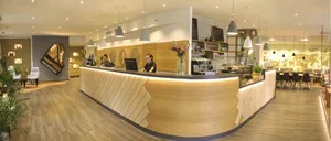 Interior view of a modern coffee shop featuring a wooden counter and seating area.