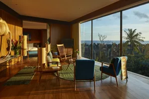 Modern living room with wooden floors, glass walls, and blinds