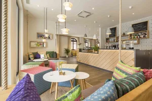 A cozy cafe interior with wooden walls, fabric seating, and metal accents.