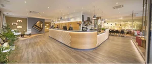 An inviting modern cafe reception area with wooden countertops, a world map backdrop, and a piano.