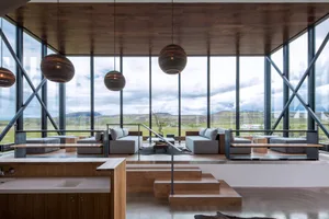 Modern living room featuring large glass windows with a view outside and wooden flooring.