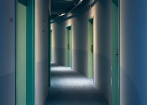 Industrial office corridor with concrete floors and green doors.