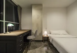 Minimalist bedroom with concrete elements and a single bed.