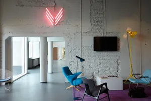 Minimalist office space featuring a concrete wall and blue chairs.