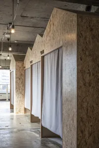 Minimalist architectural showroom with wooden structures, white curtains, and a concrete floor.
