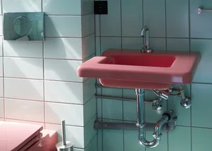Modern bathroom featuring pink ceramic tiles, a pink sink, and a pink toilet against a white tiled wall.