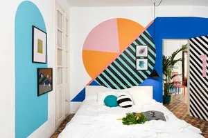 A bedroom with a colorful geometric mural painted on the wall