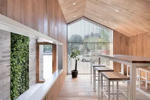 A modern cafe interior with wooden walls and a high window overlooking an outdoor area.