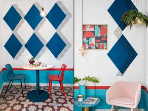 A modern coffee shop interior with blue geometric patterns on the walls and a combination of red, blue, and pink furniture.