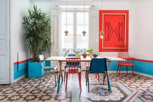 A modern dining room features a wooden table, metal chairs, and fabric-covered seating.