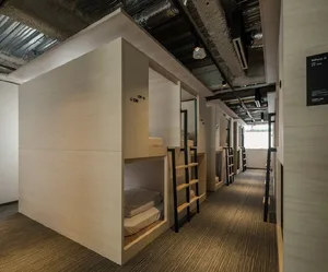 A modern dormitory room with bunk beds, wooden walls, and carpet flooring.