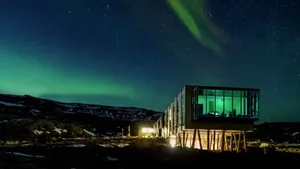 A modern house with a glass extension and green lights in the sky.
