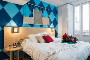 A modern bedroom with textured wallpaper, a wooden headboard, and a white bedspread.