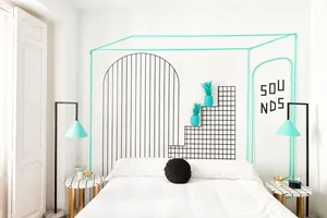A modern bedroom featuring a turquoise accent wall with a geometric wire design and metallic elements.