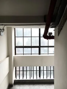 Concrete interior space featuring a window, columns, ceiling, and exposed pipes.