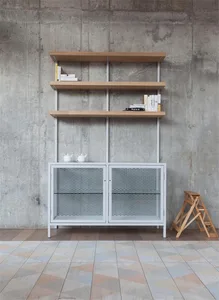 A metal bookshelf with wire mesh doors and open shelves, against a concrete wall.