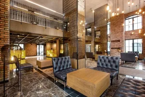 Modern industrial lobby with exposed brick walls, marble flooring, and leather seating.