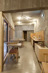 寬敞的工業風餐廳室內，擁有混凝土牆面、木製餐桌與椅子。