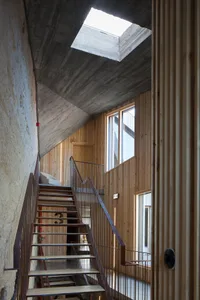 Industrial-style home interior with wood and concrete walls, concrete ceiling, and steel staircase.