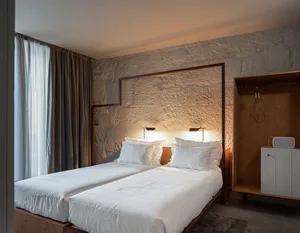 A minimalist bedroom with two twin beds, white sheets, and minimalist design features.