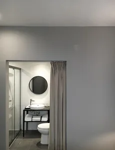 Modern minimalist bathroom with white tile walls, a glass shower door, and a sleek metallic sink.