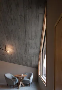 A minimalist living room with concrete walls and a small table with bowls of fruit.