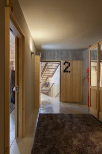 A modern residential interior featuring concrete flooring, wood walls, and metal railings.