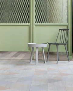 A modern interior design featuring a tiled floor, concrete furniture, and green paneling.