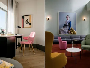 A modern living room with pink and yellow horned armchairs, a green couch, and a dark wooden table.
